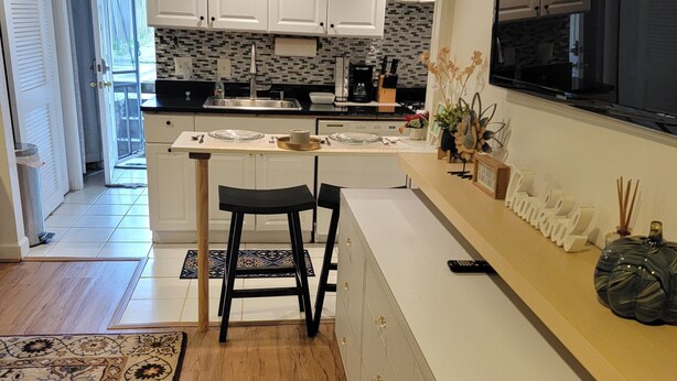 A modern kitchen with white cabinets, a central island with bar stools, a large window, and a decorative rug. - Great Delray, Alexandria, One bed, bath, kitchen NOT share, big backyard, metro, (Alexandria)