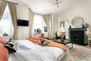 Ein Schlafzimmer mit einem Bett, einem Couchtisch mit Tablett, einem Kamin und einem an der Wand befestigten Fernseher.