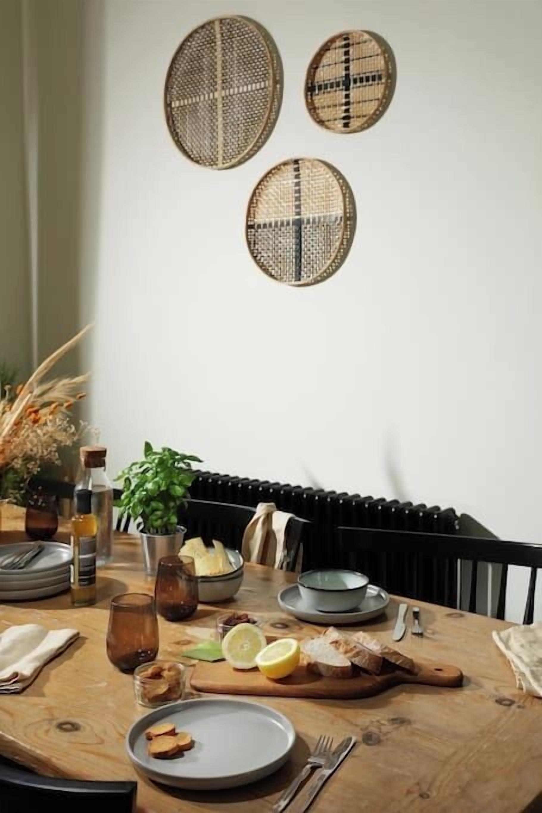 A dining table with plates, glasses, and cutlery, accompanied by a bowl of food and a bottle.