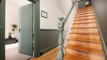 Una escalera de madera con una puerta verde que da a una habitación.