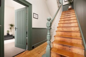 Una escala de fusta amb una porta verda que dona a una habitació.