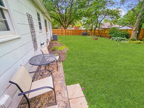 A backyard with a patio table and chairs, a wooden fence, and a lawn. - The Aviary Cottage: Bunkbed, Near Playground, Swing, Full Fence, Central to all (Springfield)