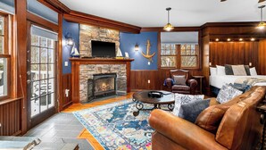 Una sala de estar acogedora con chimenea de piedra, mobiliario de cuero y decoración náutica.