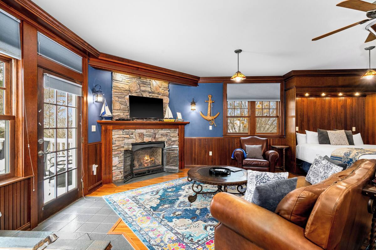 A cozy living room with a stone fireplace, leather furniture, and nautical decor.