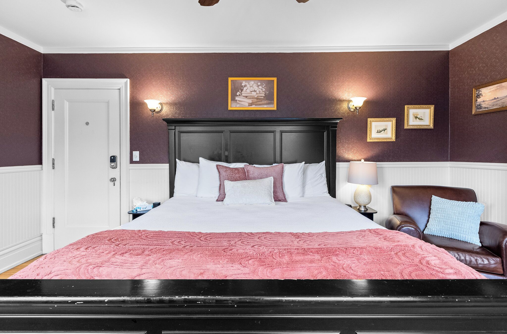 Een slaapkamer met een bed, een stoel, een nachtkastje en wandlampen.