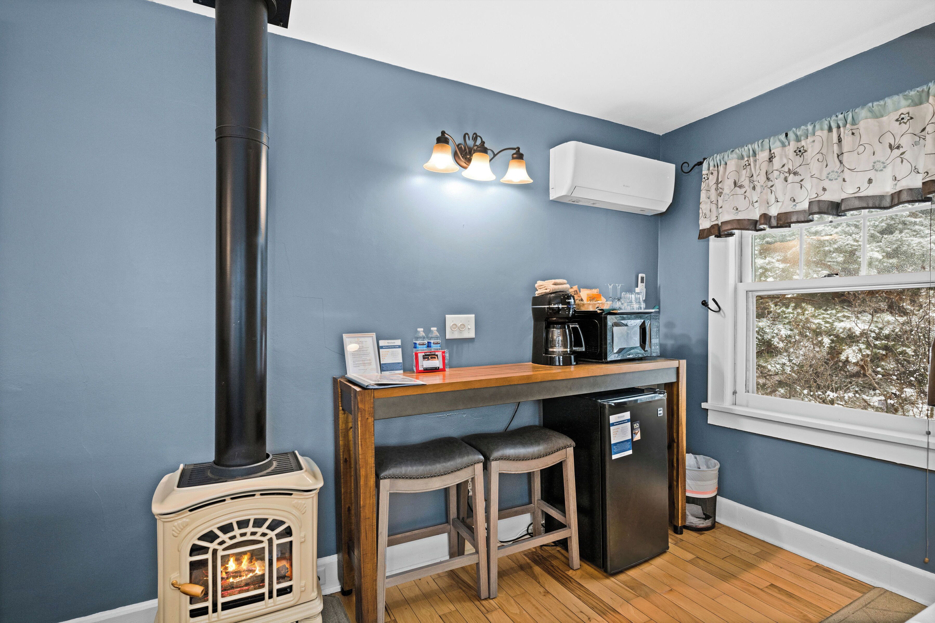 A kitchen with a wood-burning stove, a coffee maker, and a refrigerator.