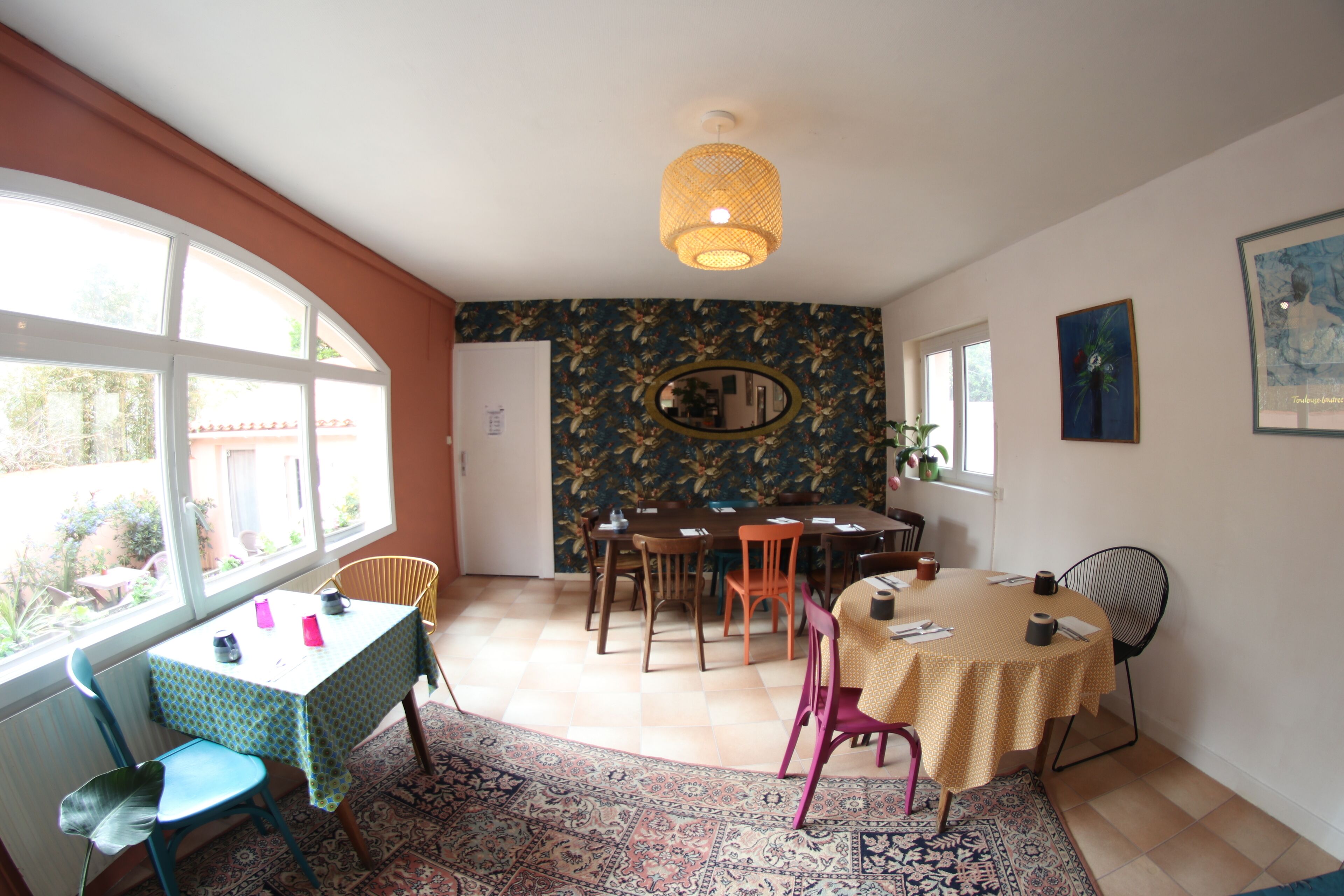 Un espace repas comprenant une table et des chaises, un tapis à motifs et un luminaire suspendu.