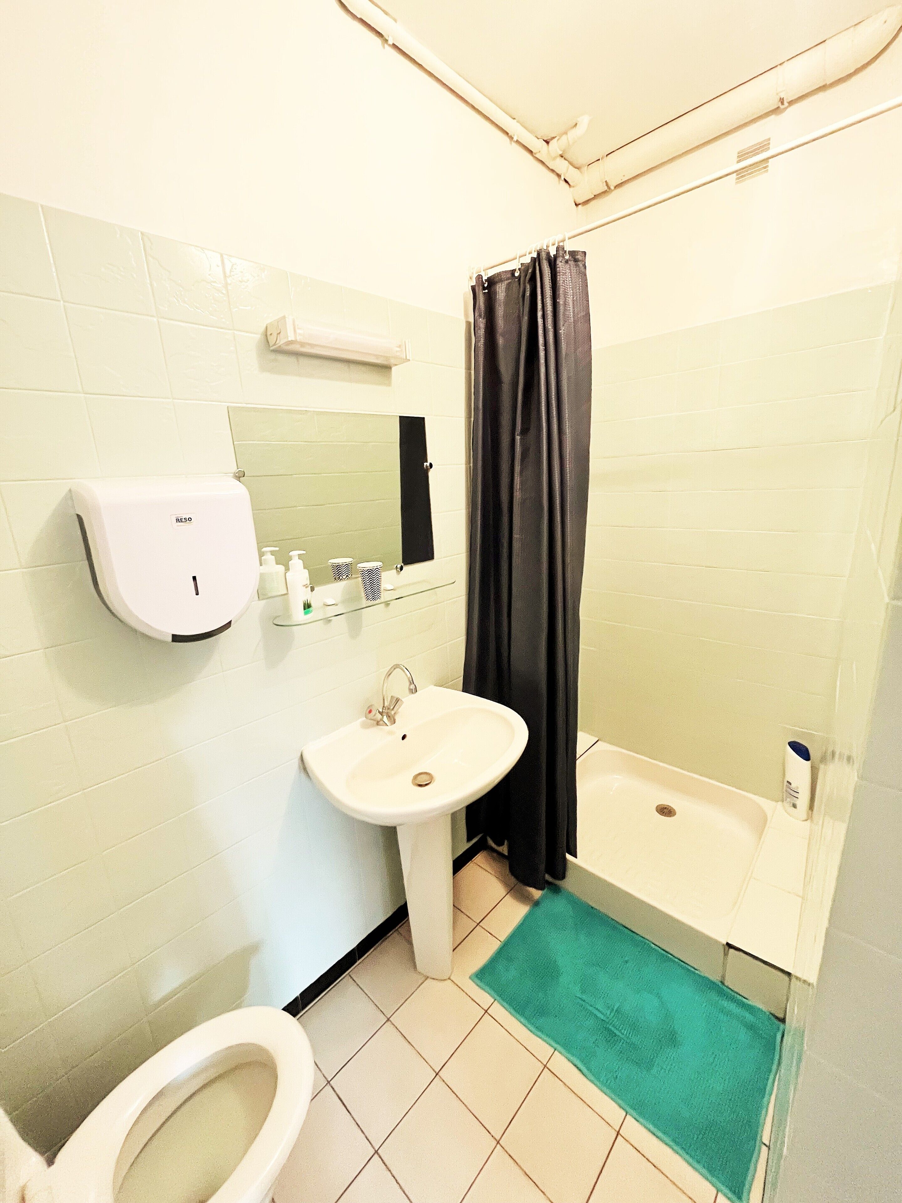 Et badeværelse med vask, spejl, toilet og badekar.