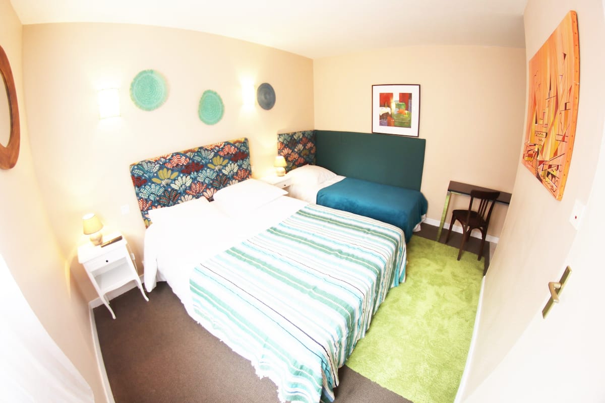 Une chambre à coucher avec un lit, des tables de chevet, une chaise et une moquette verte.
