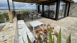 A covered outdoor seating area with a table and chairs, a sofa, and a view of the city. - Villa Dammuso with pool in Val di Noto (Avola)