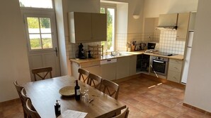 Cucina compatta con zona pranzo, con tavolo e sedie in legno, forno integrato e finestra che offre luce naturale.