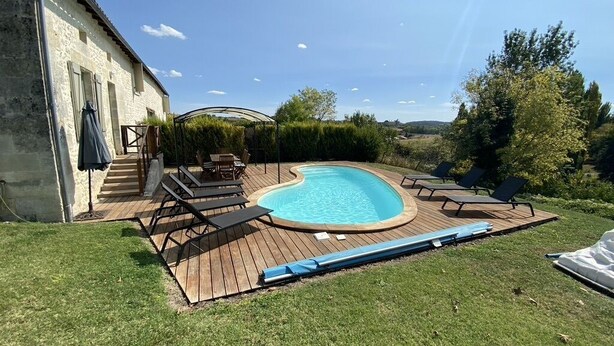 Un giardino con piscina, terrazza in legno e mobili da esterno.