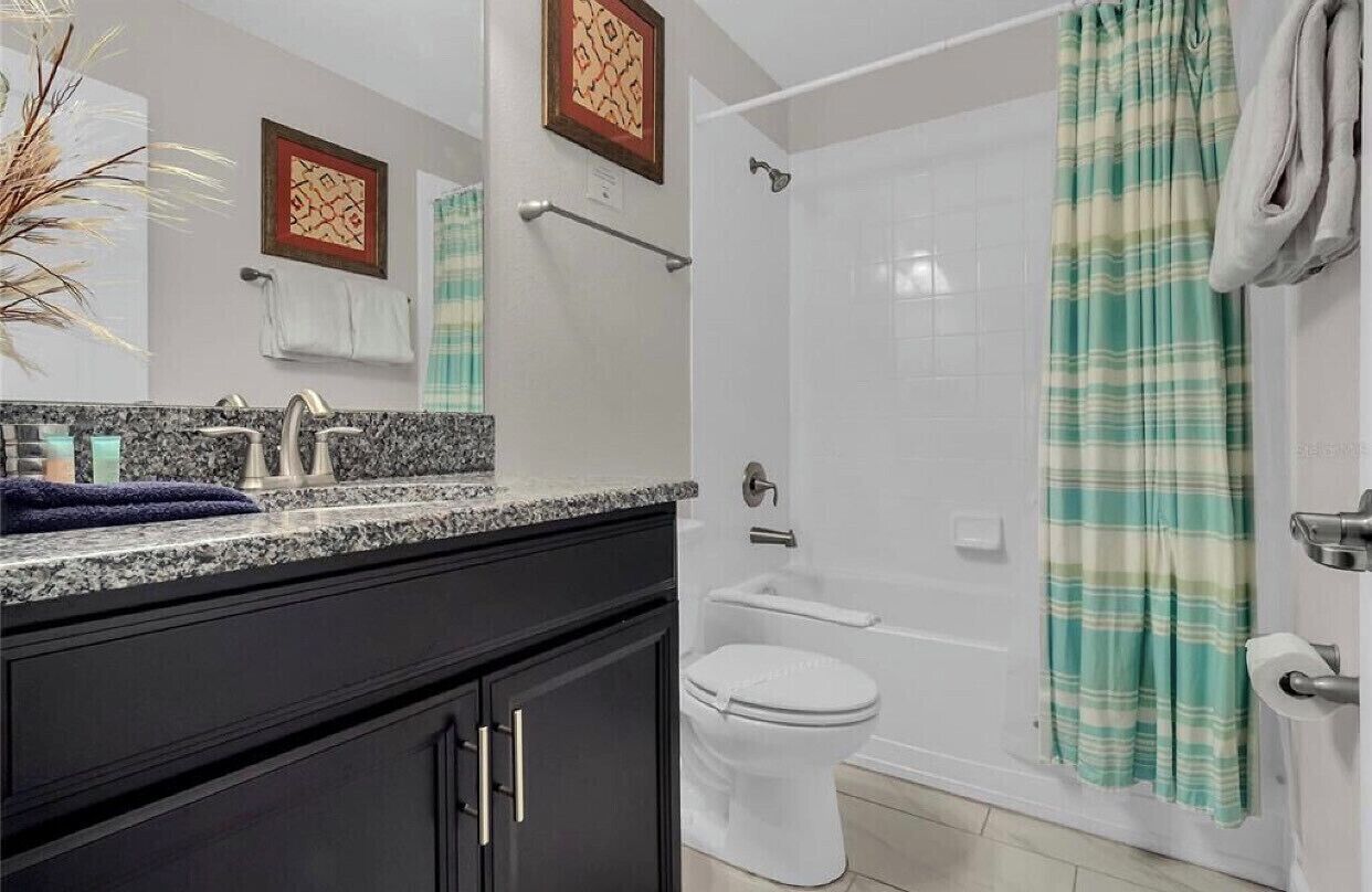 A bathroom with a shower, toilet, and sink.