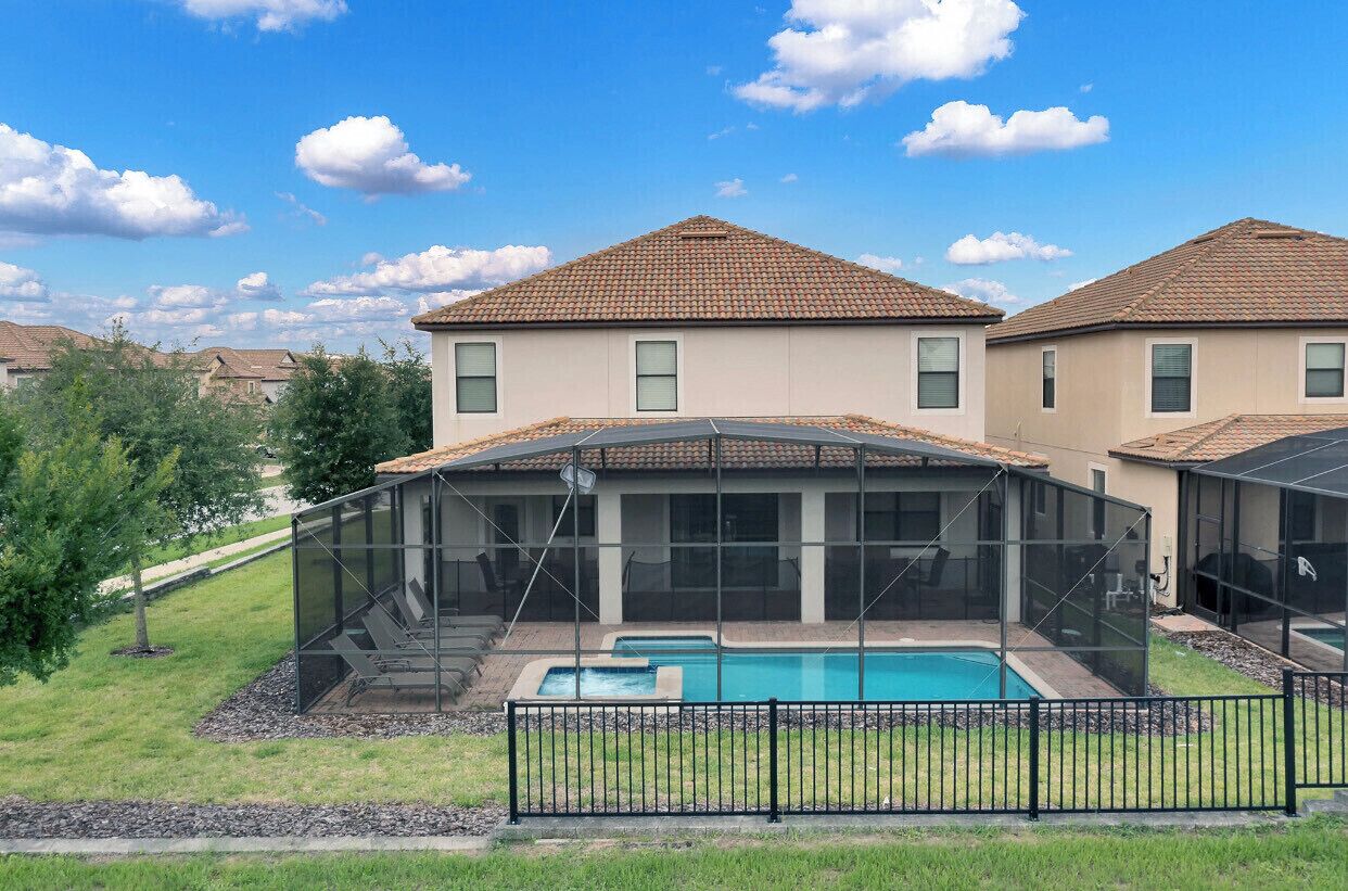 A residential property with a swimming pool, enclosed patio, and a fenced backyard.