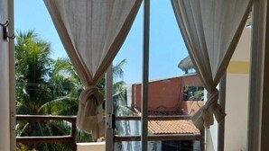 A room with a sliding glass door leading to a balcony, curtains, a bench, and an air conditioning unit. - Brisamar Guesthouse (Puerto Escondido)