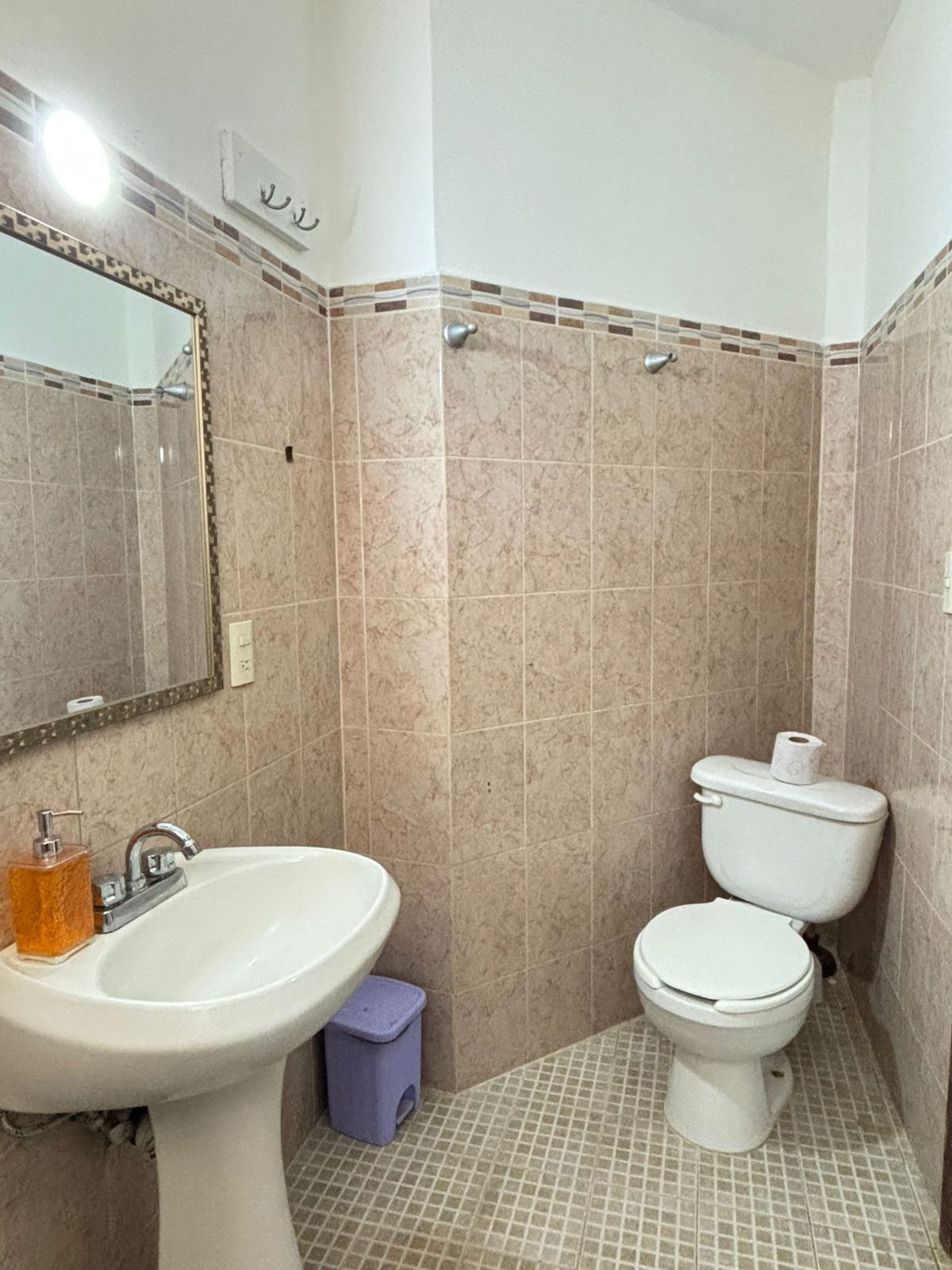 Un baño con lavamanos, espejo y dos inodoros.