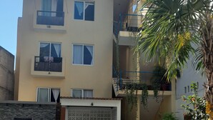 A multi-story building with a swimming pool, outdoor seating, and a staircase leading to the upper floors. - Brisamar Guesthouse (Puerto Escondido)