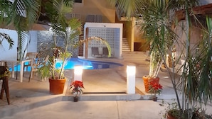 A pool area with a seating area and potted plants. - Brisamar Guesthouse (Puerto Escondido)
