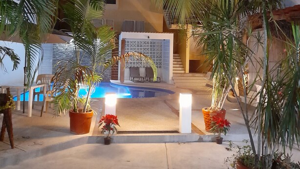 A pool area with a seating area and potted plants. - Brisamar Guesthouse (Puerto Escondido)