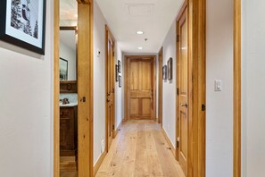 Un couloir avec des portes en bois, un coin cuisine et des tableaux encadrés accrochés aux murs.