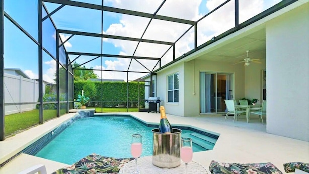 Ein Swimmingpool mit Glasveranda, eine Champagnerflasche und zwei Gläser auf einem Tisch.