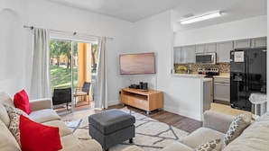 A modern living room with a sofa, ottoman, and a flat-screen TV. - RP144BD - Disney Regal Palms Townhome near Disney - Come on by! (Davenport)