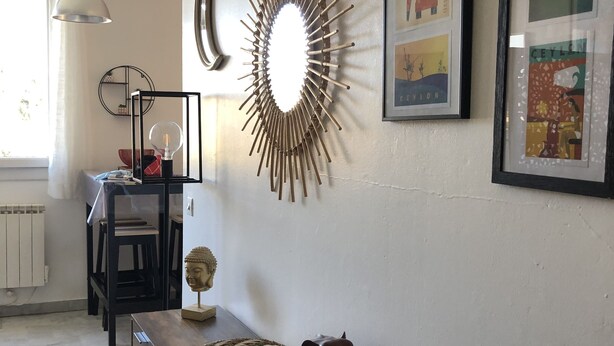Een moderne woonkamer met een houten console tafel, een decoratief wandobject en ingekaderde kunstwerken.