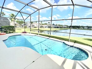 Piscina com vista para um lago e casas ao fundo.