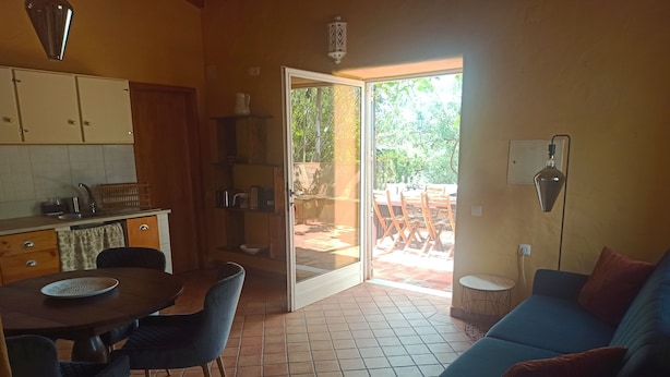 A compact living space with a dining area, a sofa, and a sliding glass door leading to an outdoor patio.