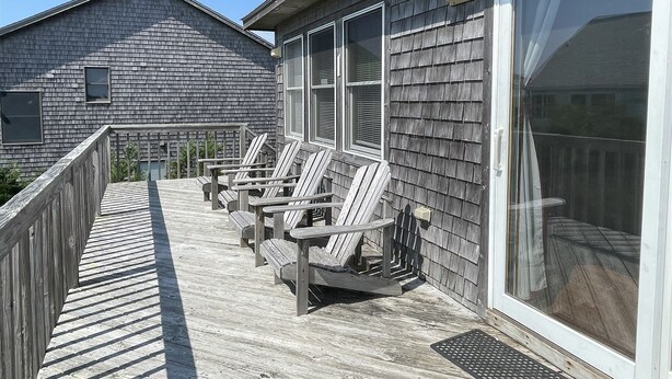 A wooden deck with Adirondack chairs, a large sliding glass door, and a building with a shingled exterior. - Swinkels is a spacious 3 bedroom, 1.5 bath home that is a true jewel! (FRISCO)
