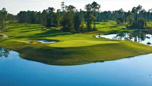A golf course with a pond, surrounded by trees. - 7BR Champions Gate Resort/Private Pool & Spa/15 min to Disney/Sleeps 16+ (Davenport)