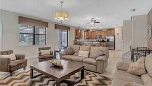 A spacious living room with a sofa set, a coffee table, and a chandelier. - 7BR Champions Gate Resort/Private Pool & Spa/15 min to Disney/Sleeps 16+ (Davenport)
