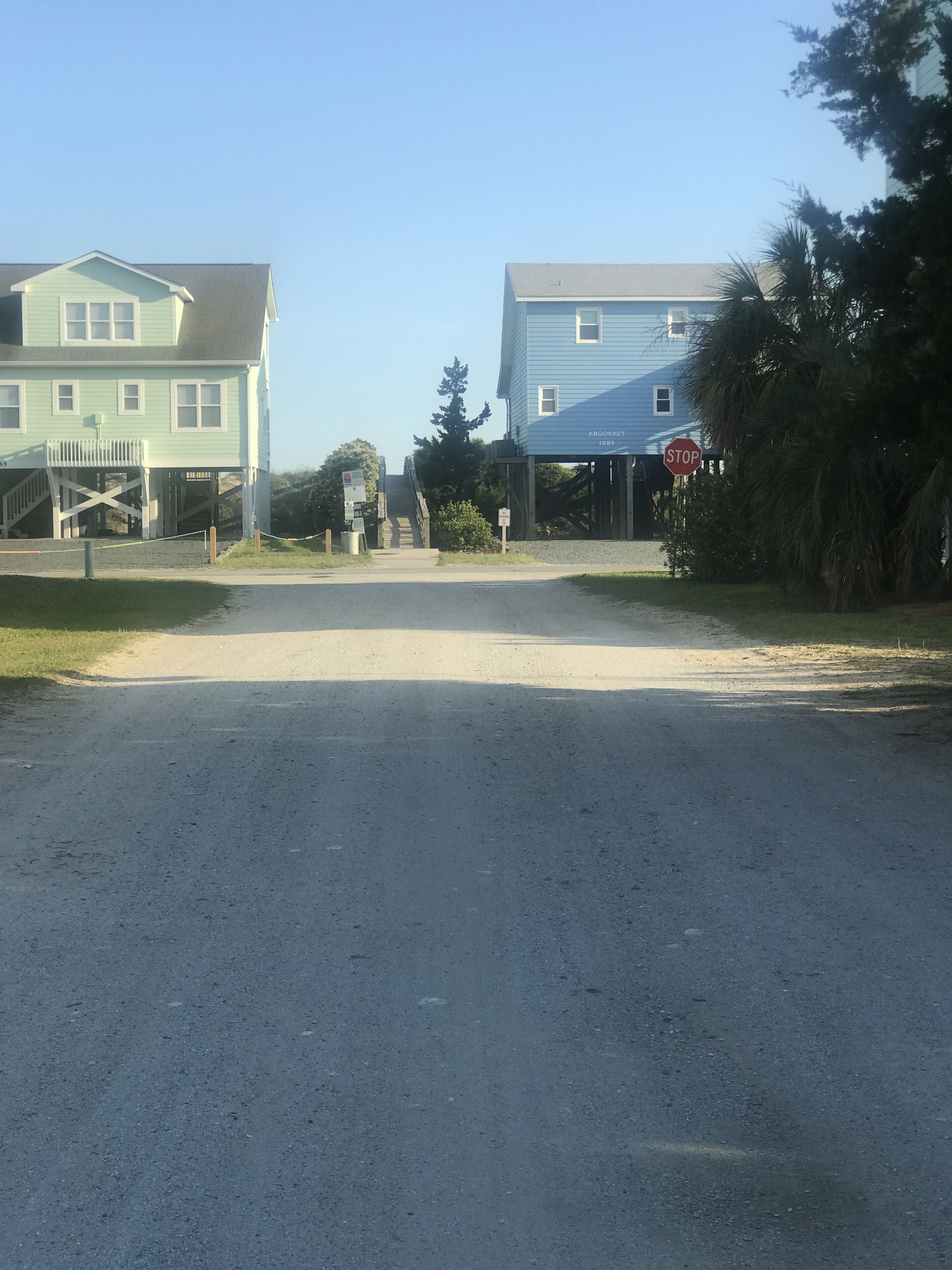 A gravel road leading to a stop sign with two houses on either side.