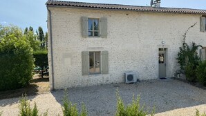 A two-story building with a gravel driveway and a small garden area. - Les Houx - Old barn with private swimming pool (Chalais)