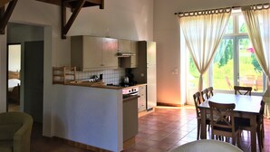 A spacious kitchen with a central island, wooden chairs, and a dining table. - Les Houx - Old barn with private swimming pool (Chalais)