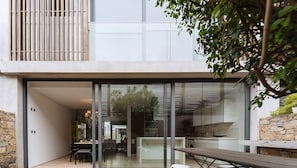Uma casa moderna com uma grande porta de vidro que dá para uma sala de jantar com mesa e cadeiras de madeira.