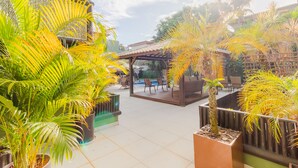 A courtyard with potted palm trees, outdoor seating, and a pool area. - PF36 Ótimo Quarto e Sala a 25m da Praia (Mata de São João)