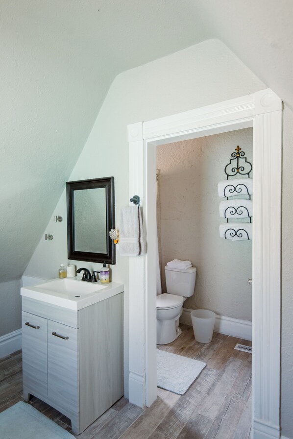 A bathroom with a white vanity, a dark-framed mirror, a white toilet, and a white sink.