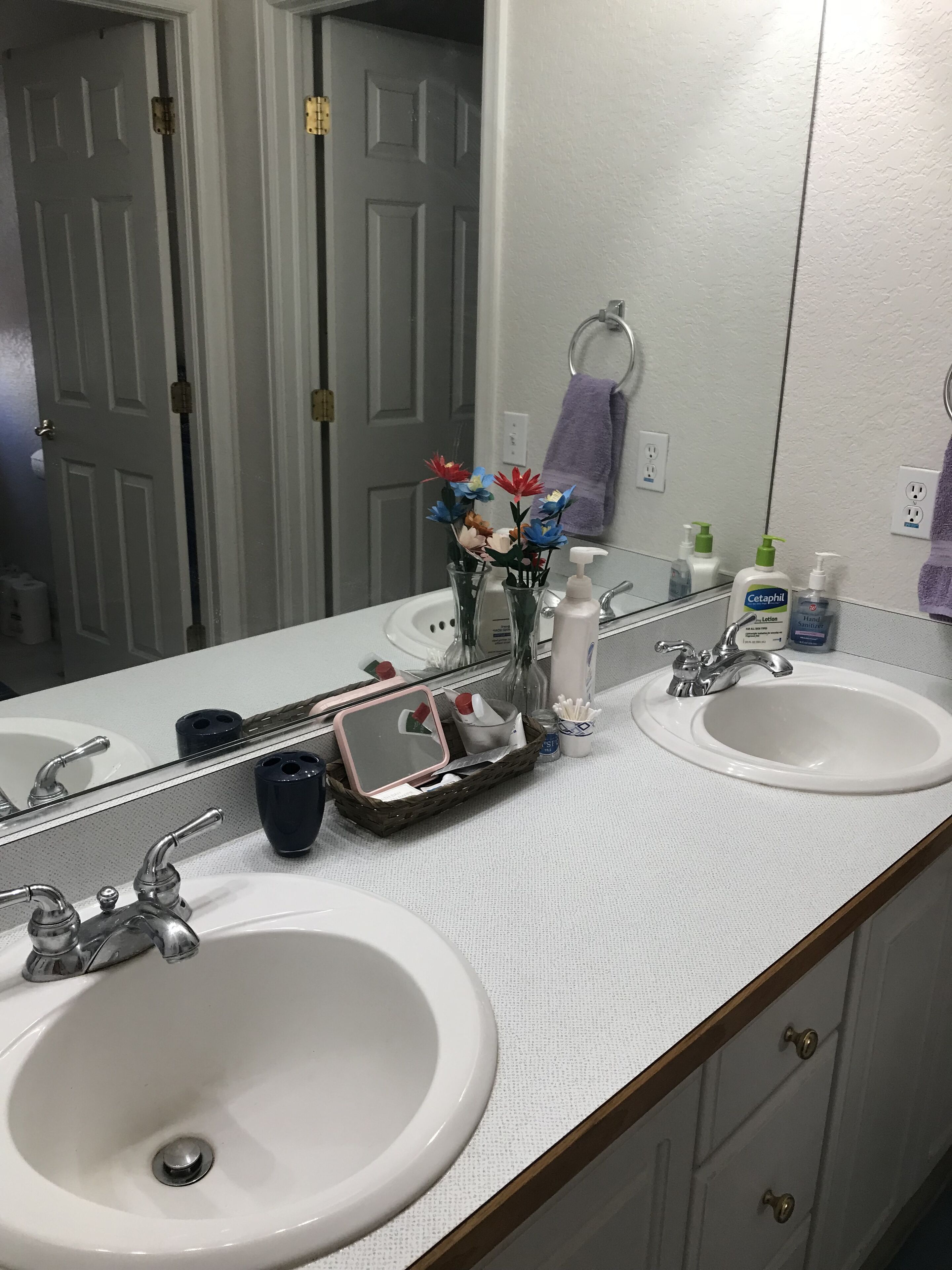 A bathroom with two sinks, a mirror, and toiletries.