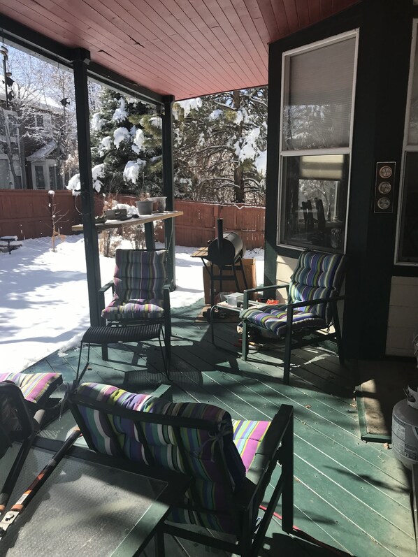 A covered outdoor seating area with striped chairs and a barbecue grill. - Nice bedroom and bath in large 2 story house (Centennial)