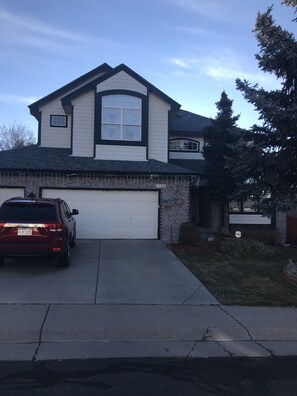 A two-story house with a garage, a driveway, and a car parked in front. - Nice bedroom and bath in large 2 story house (Centennial)