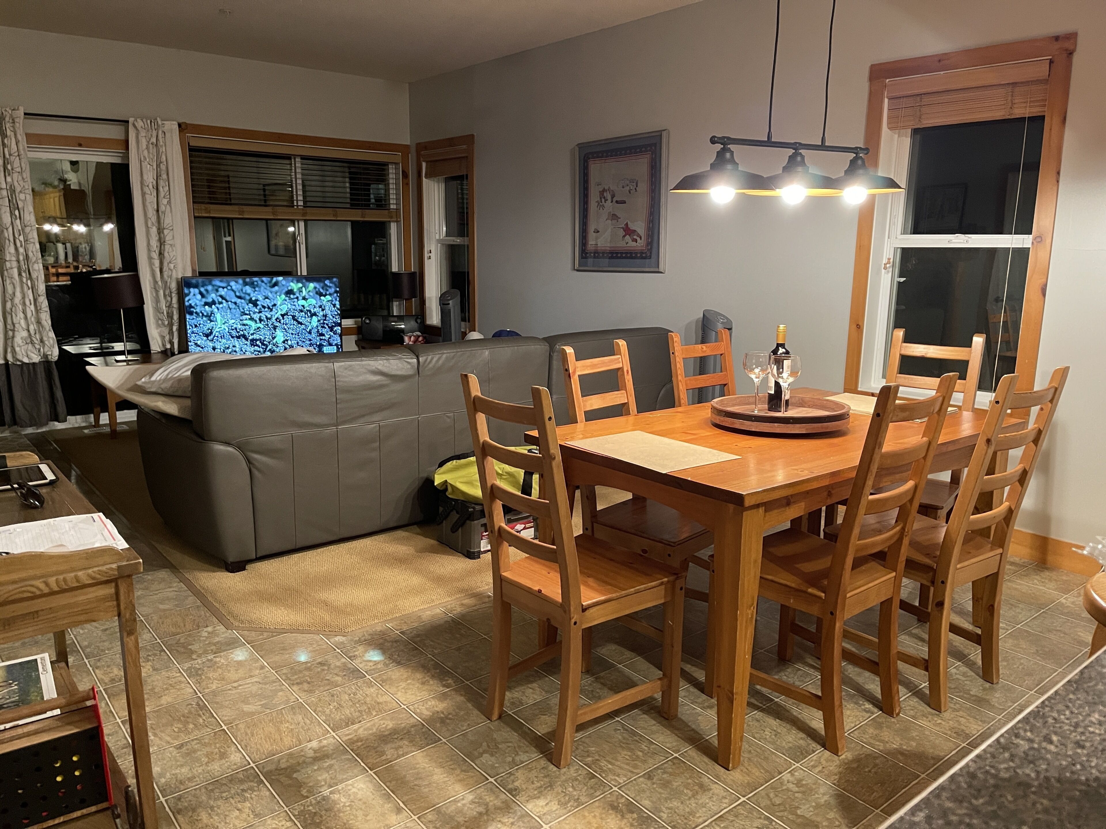 Un salon comprenant un canapé, un téléviseur, une table à manger en bois et des chaises.