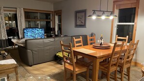 Un salon comprenant un canapé, un téléviseur, une table à manger en bois et des chaises.