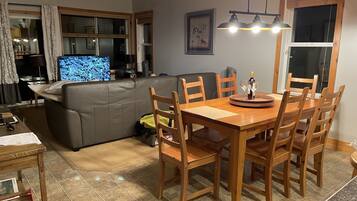Un salon comprenant un canapé, un téléviseur, une table à manger en bois et des chaises.