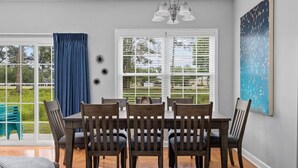 Un comedor con mesa y sillas, ventanas amplias y una lámpara en el techo.