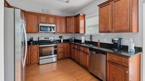 Una cocina con gabinetes de madera, electrodomésticos de acero inoxidable y encimera de granito.