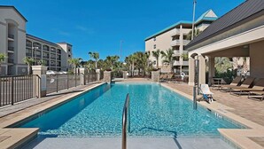 Una piscina con agua cristalina, rodeada de sillas de descanso y una cerca.