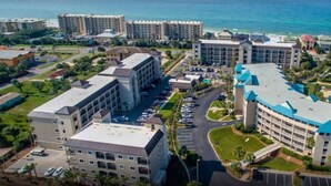 Un complejo hotelero con varias edificaciones, zonas de estacionamiento y vista al océano.