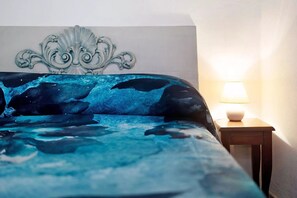 Cozy retreat with a bed featuring a unique abstract design, paired with a decorative headboard and a simple nightstand with a lamp.