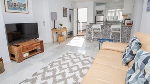 A modern living room with a TV, sofa, and patterned rug. - Los Flamencos apto N56 (Manilva)